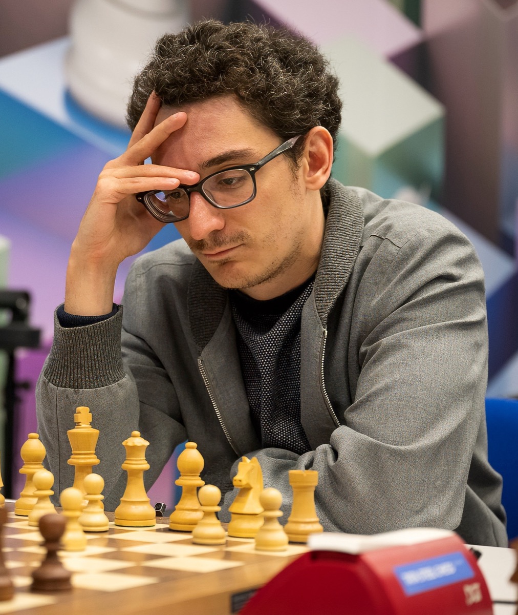 Fabiano Caruana at the board at the 2025 Tata Steel Chess Tournament, chin on hand, in glasses and a grey cardigan